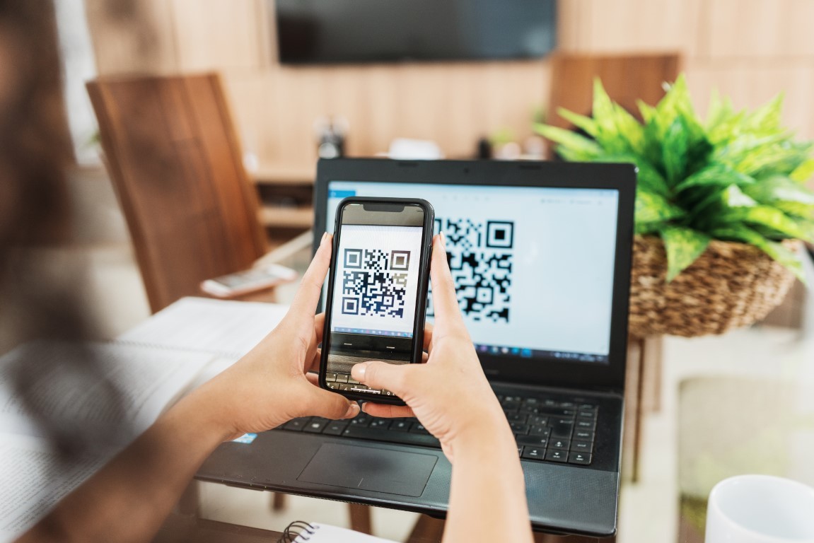 A person scanning a QR code on their laptop screen.